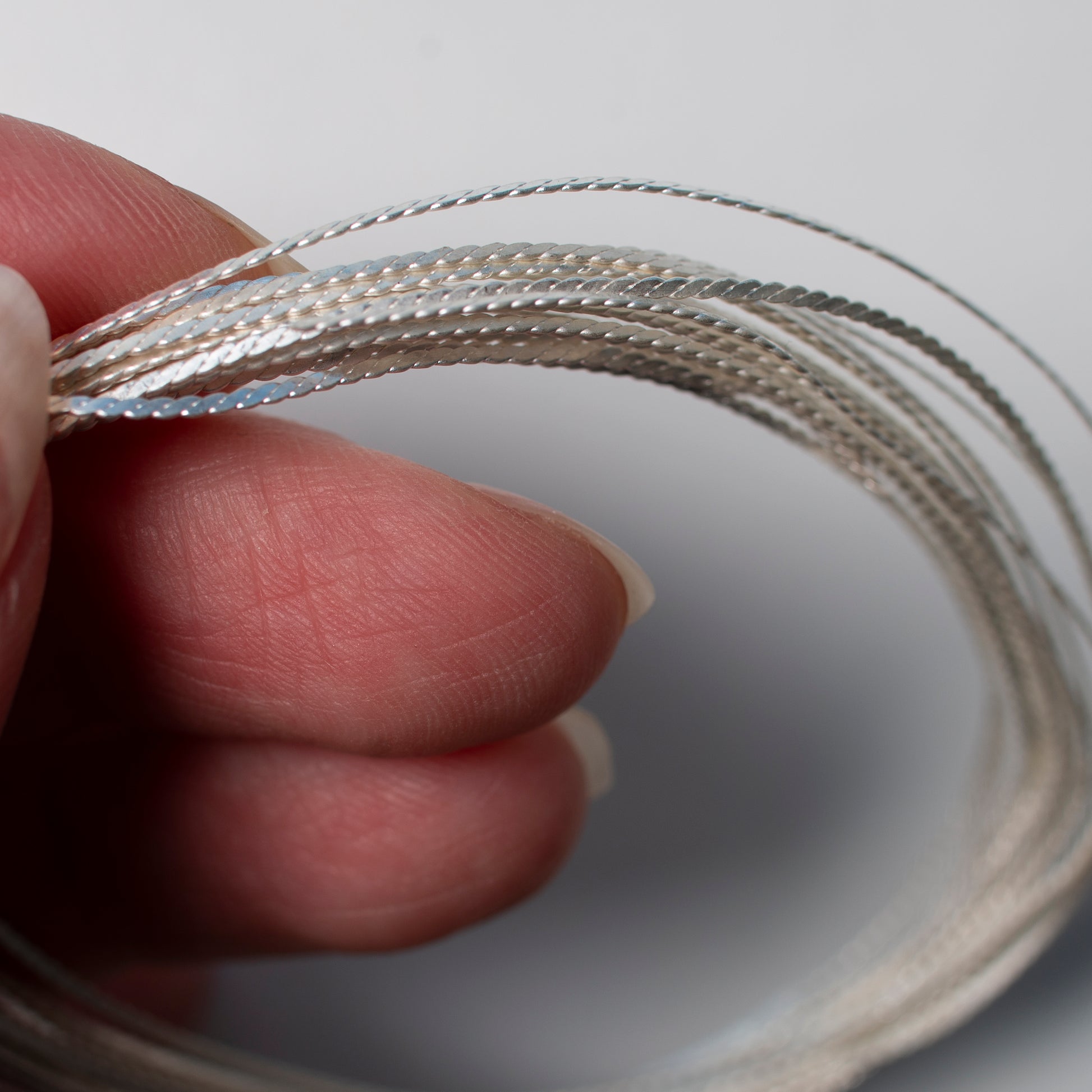Hand holding a wire of silver filigree
